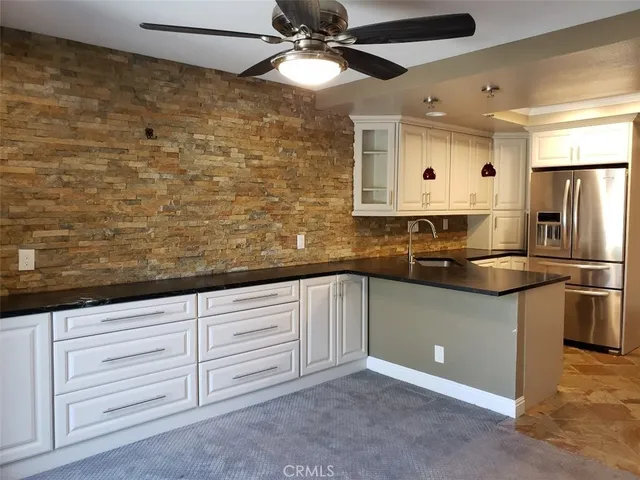 a kitchen with stainless steel appliances granite countertop a refrigerator a stove and a sink