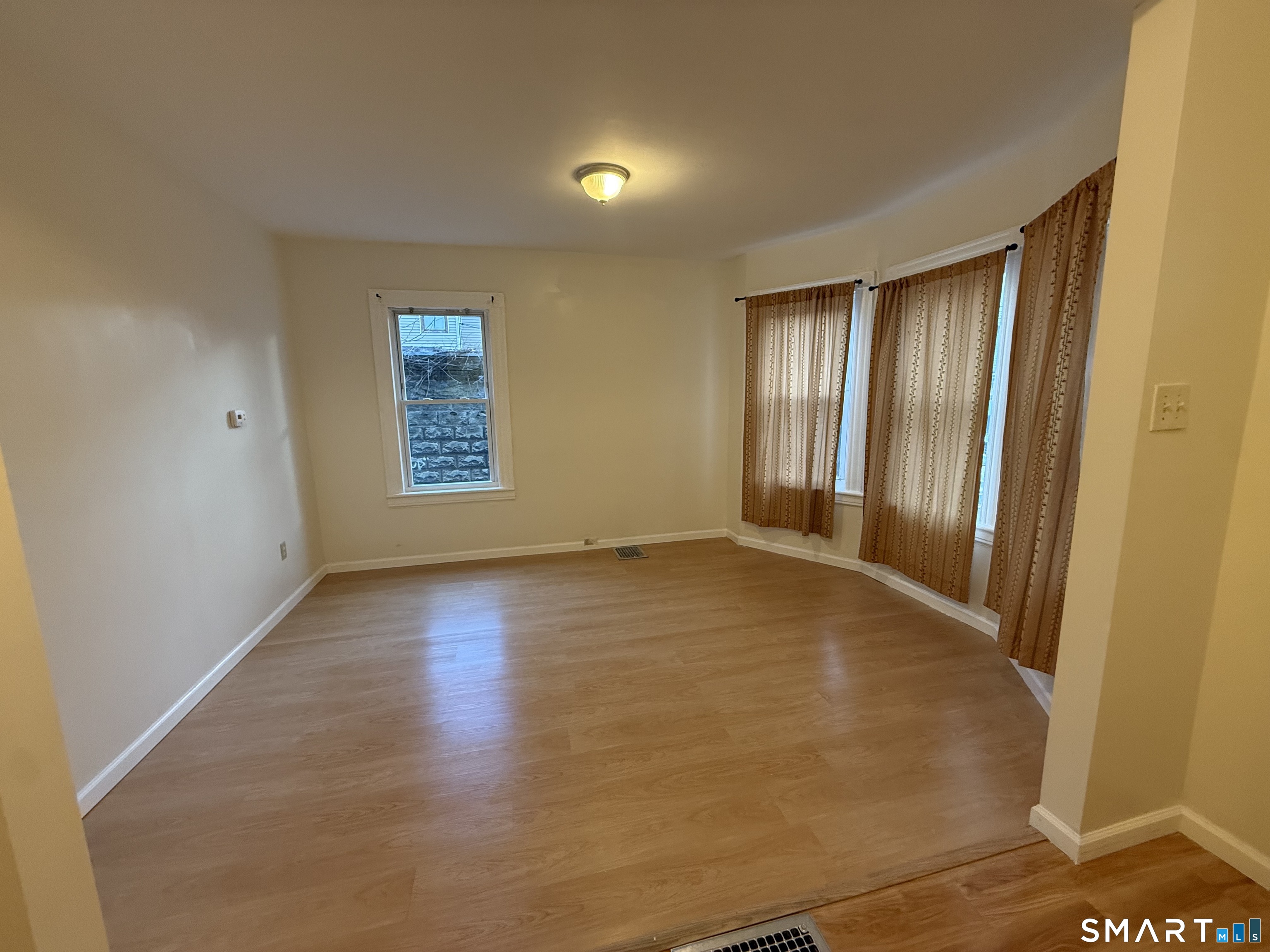 180 5th Street, Unit 1 Bridgeport, CT 06607 - Photo 8 of 26 an empty room with wooden floor and windows