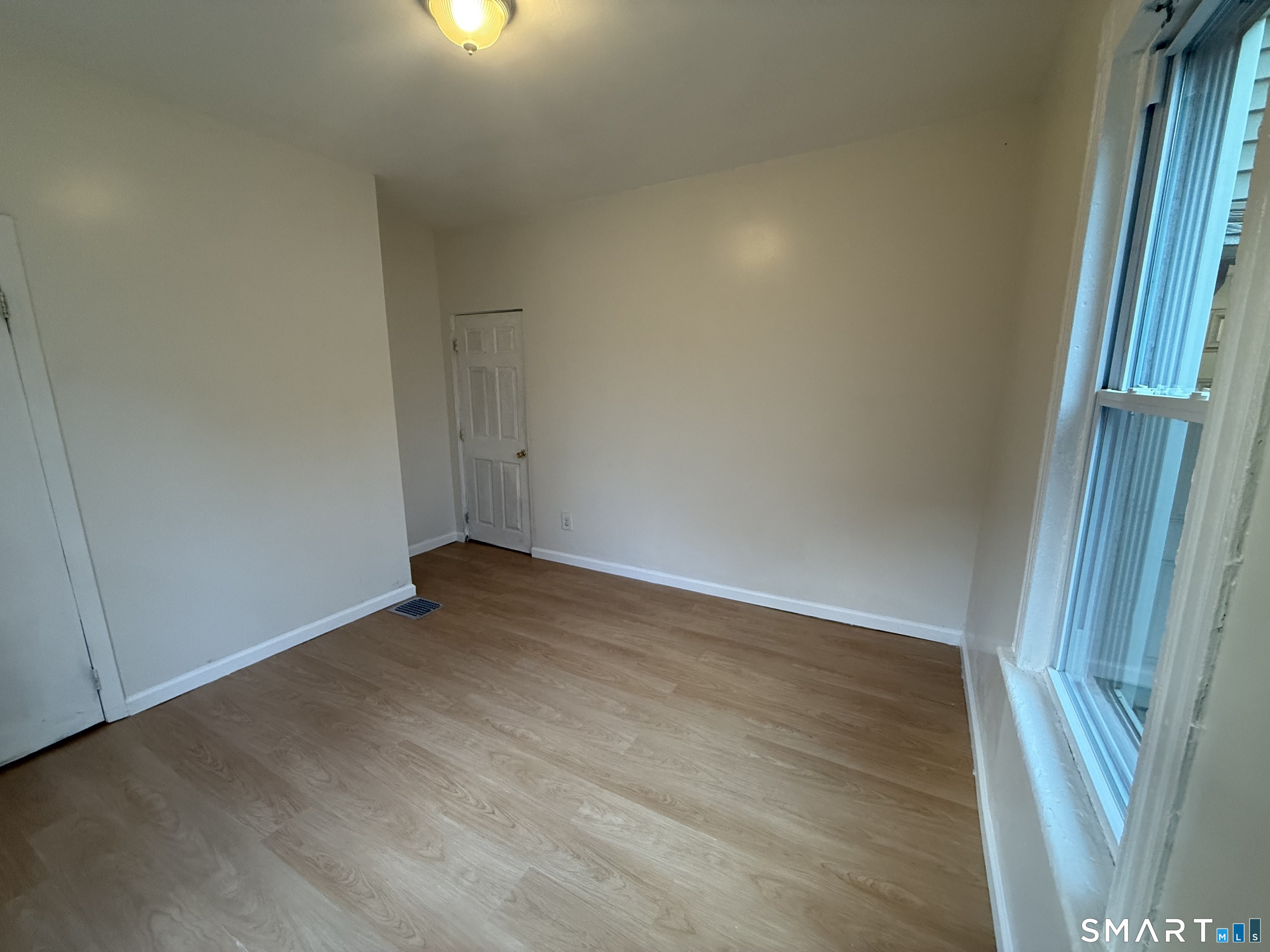 180 5th Street, Unit 1 Bridgeport, CT 06607 - Photo 10 of 26 an empty room with wooden floor and windows