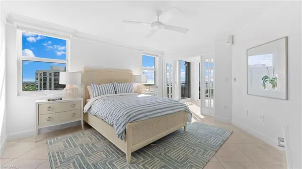 a bedroom with a large bed and a chandelier fan