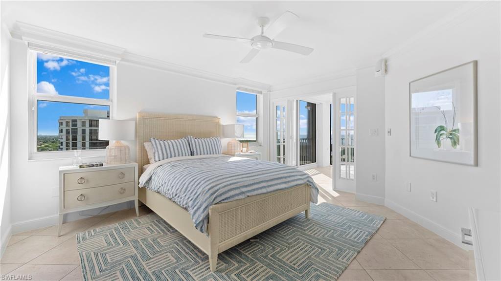 6101 Pelican Bay Boulevard, Unit 1404 Naples, FL 34108 - Photo 11 of 22 a bedroom with a large bed and a chandelier fan
