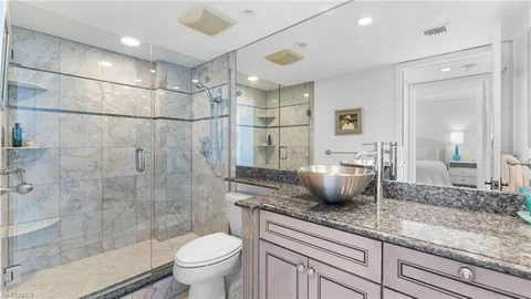 a bathroom with a granite countertop sink a toilet and shower