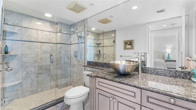 a bathroom with a granite countertop sink a toilet and shower