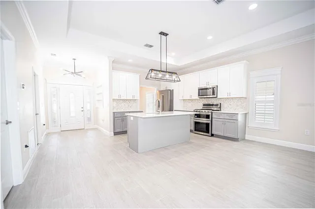 a kitchen with stainless steel appliances kitchen island a refrigerator sink and cabinets