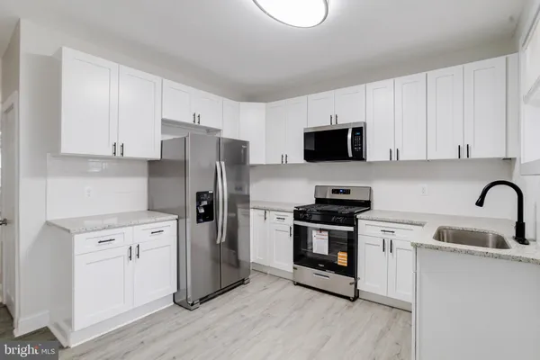 a kitchen with a refrigerator stove and sink with wooden floor