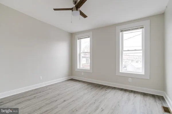 a view of an empty room with wooden floor and window