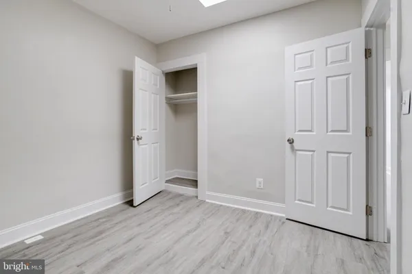 an empty room with wooden floor and closet area