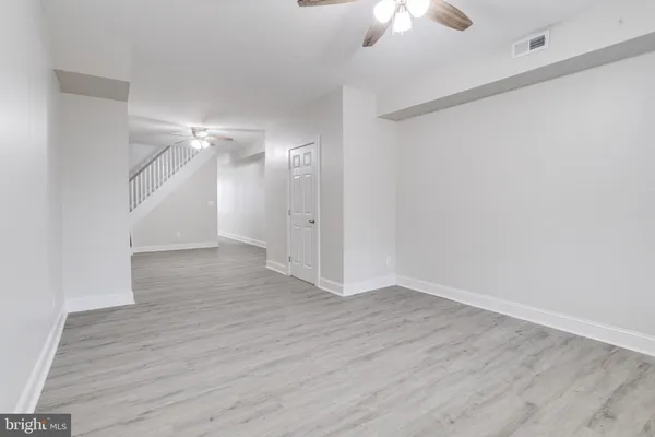 wooden floor in an empty room with a chandelier fan