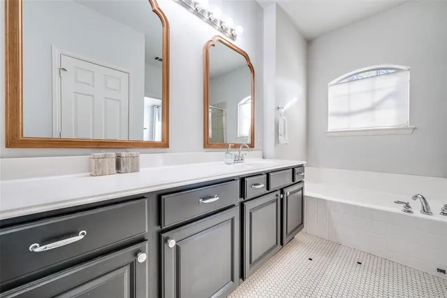 a bathroom with a double vanity sink a mirror and a bathtub
