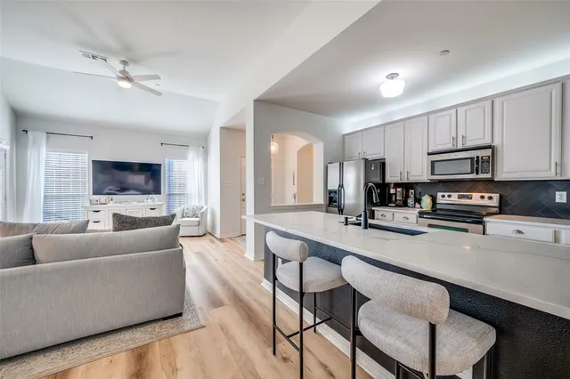 a living room with stainless steel appliances a dining table a computer on a desk and kitchen view