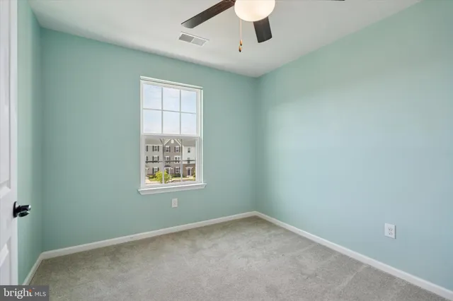 an empty room with a window and ceiling fan