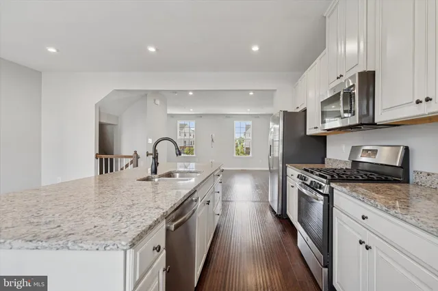 a large kitchen with stainless steel appliances granite countertop a lot of counter space and wooden floors