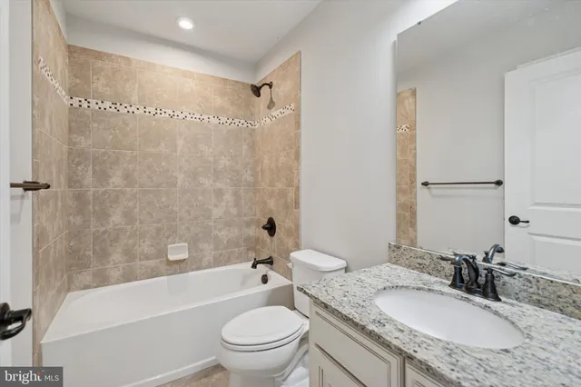 a bathroom with a granite countertop sink toilet mirror and bathtub