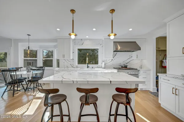 a kitchen with a stove a chandelier and living room view
