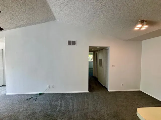 a view of an empty room with wooden floor and a carpet