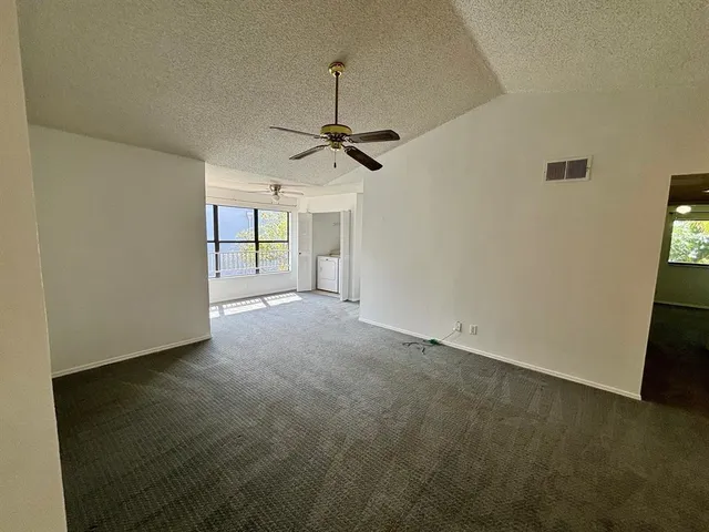an empty room with a ceiling fan and carpet