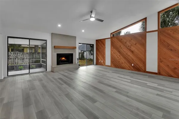 a view of an empty room with wooden floor fireplace and a window