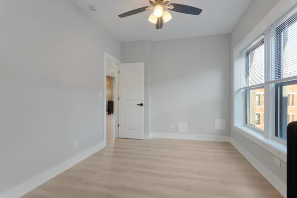an empty room with chandelier fan and windows
