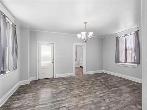 a view of an empty room with window and wooden floor