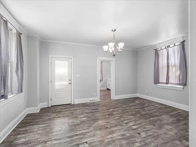 a view of an empty room with window and wooden floor