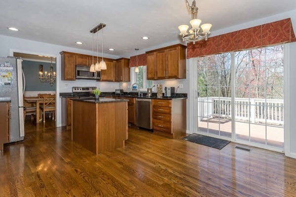 226 Daniels Street Franklin, MA 02038 - Photo 7 of 24 a kitchen with stainless steel appliances granite countertop a stove top oven a sink and a dining table with wooden floor