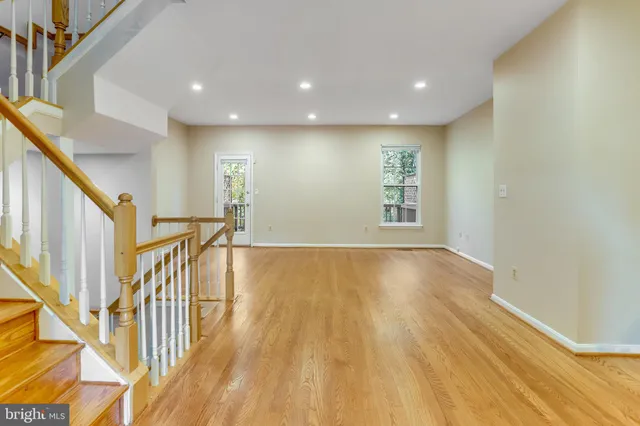 a view of an empty room with wooden floor and stairs