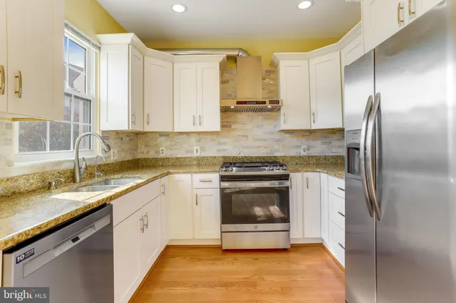 a kitchen with stainless steel appliances granite countertop a stove a sink and a refrigerator