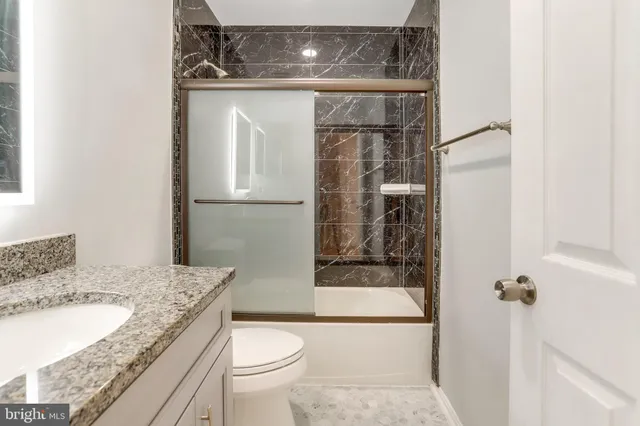 a bathroom with a granite countertop sink toilet and shower