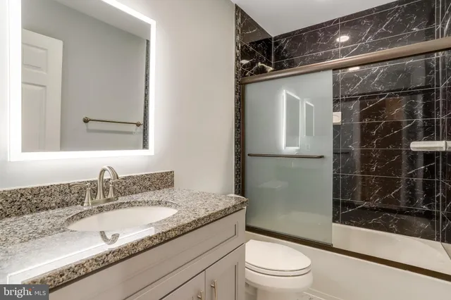 a bathroom with a granite countertop sink toilet and shower