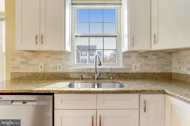 a kitchen with granite countertop a sink window and cabinets