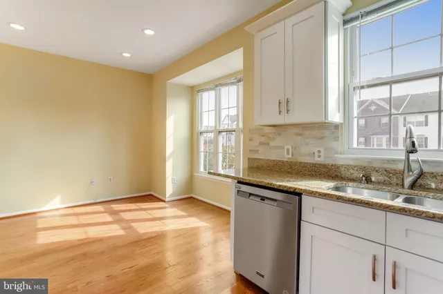 a kitchen with granite countertop a sink window and cabinets