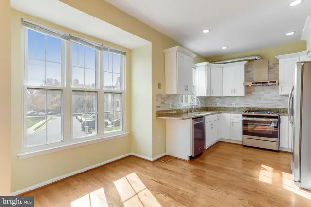 a kitchen with stainless steel appliances granite countertop a stove a sink and a refrigerator with wooden floors