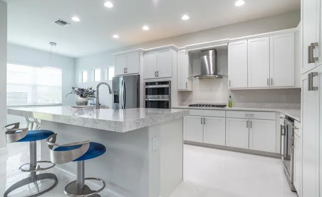 a kitchen with stainless steel appliances kitchen island granite countertop a refrigerator sink and white cabinets