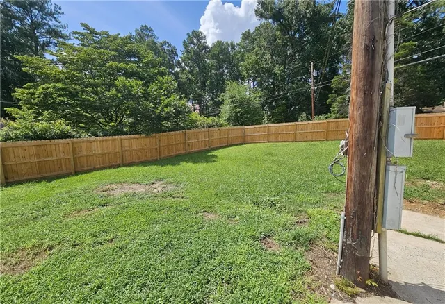 a view of yard with large trees and wooden fence