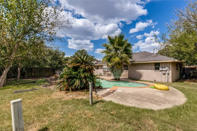 a view of a house with a yard and palm trees