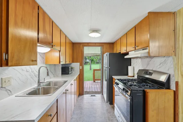 a kitchen with stainless steel appliances granite countertop a sink stove and refrigerator