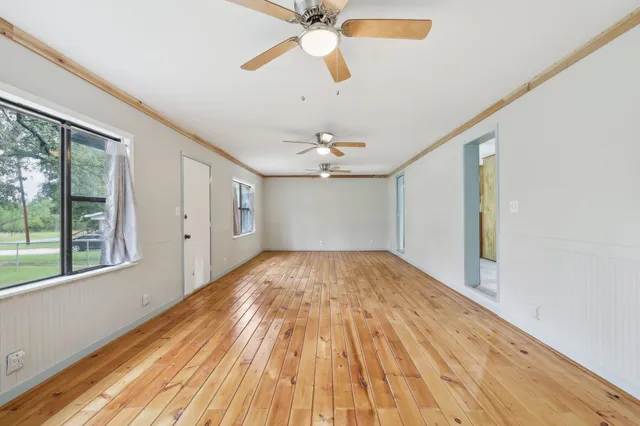 a view of empty room with wooden floor and fan
