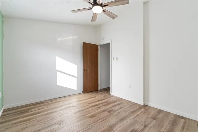 an empty room with wooden floor chandelier fan and windows
