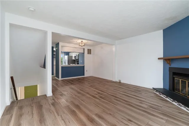 a view of an empty room with window and wooden floor