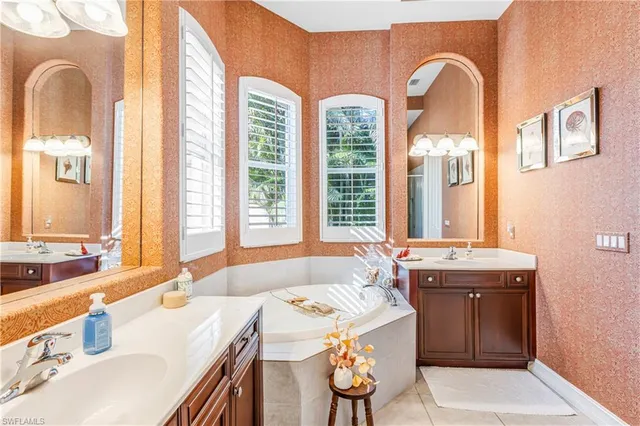 a spacious bathroom with a granite countertop sink a large mirror a bathtub and window