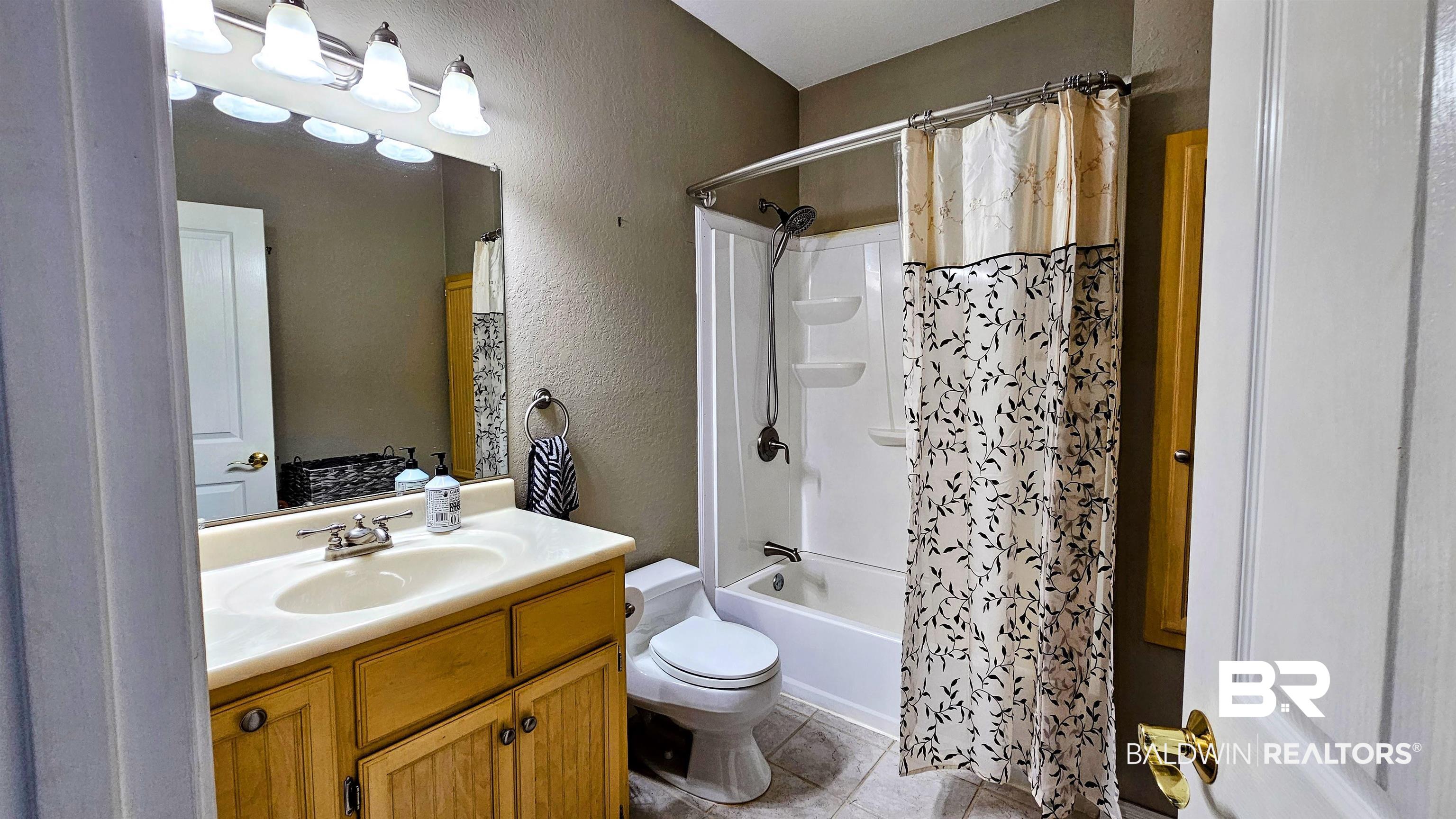 9275 Crawford Road Elberta, AL 36530 - Photo 24 of 28 Bathroom featuring a textured wall, vanity, shower / bath combo, and light tile patterned floors