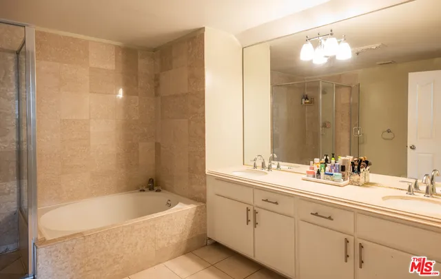 a bathroom with a double vanity sink mirror and bathtub