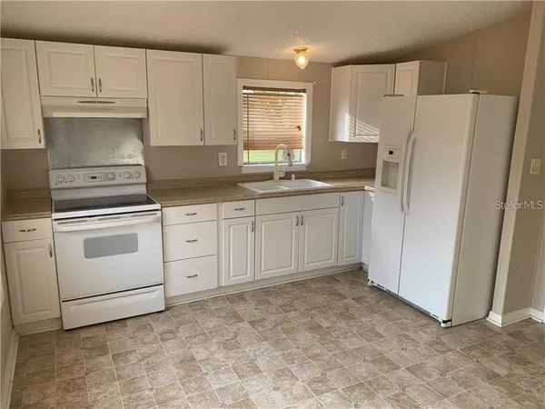a kitchen with white cabinets and white appliances