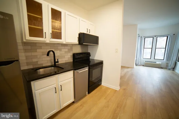 a kitchen with granite countertop a sink and wooden floors