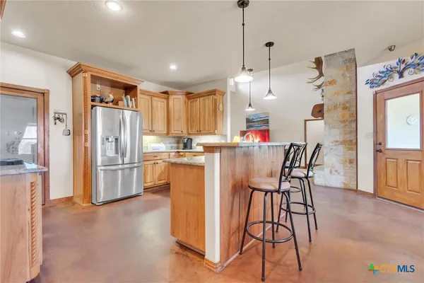 a kitchen with stainless steel appliances kitchen island granite countertop a refrigerator a stove top oven a sink dishwasher and white cabinets with wooden floor