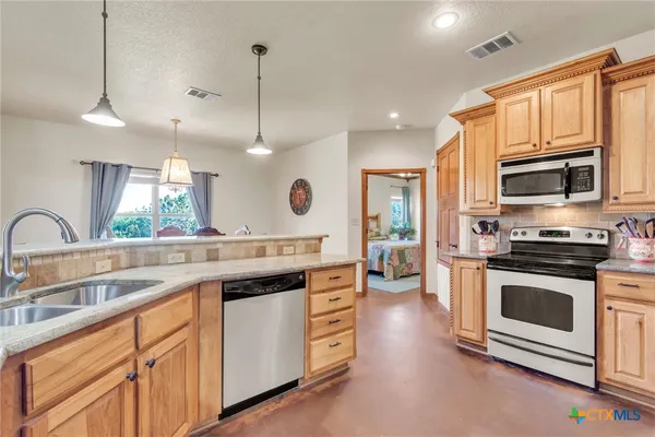 a kitchen with stainless steel appliances granite countertop a stove a sink and a microwave