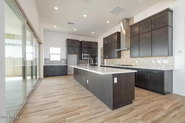 a large kitchen with stainless steel appliances kitchen island granite countertop a large counter top and wooden floors