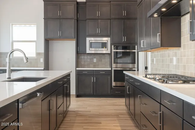 a kitchen with stainless steel appliances granite countertop a sink stove and cabinets