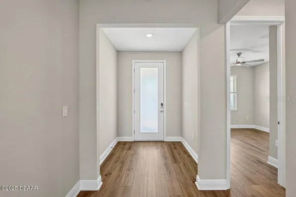 a view of an empty room with wooden floor and a window