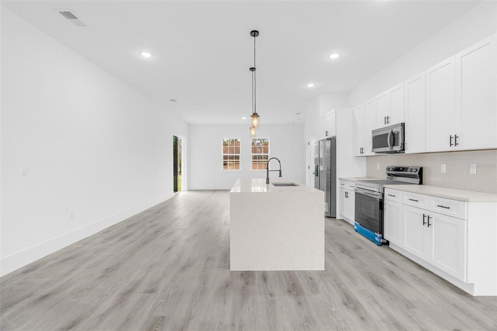 3172 Southwest 137th Loop Ocala, FL 34473 - Photo 6 of 38 a large kitchen with white cabinets a sink dishwasher a stove and a refrigerator with wooden floor